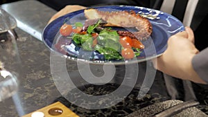A waiter serving food to people in a restaurant. Close-up of a waiter putting plates of food on the table in a cafe. The