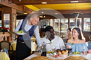 Waiter serving meals for couple at restaurant