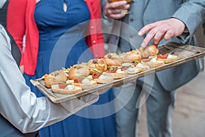Waiter serving mini sandwiches to the hosts