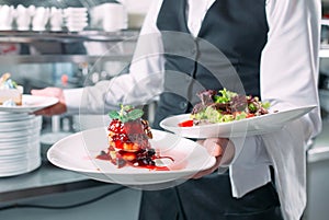 Waiter serving in motion on duty in restaurant. The waiter carries dishes.