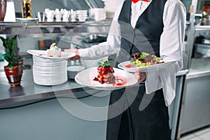 Waiter serving in motion on duty in restaurant. The waiter carries dishes.