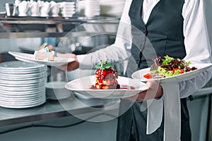 Waiter serving in motion on duty in restaurant. The waiter carries dishes.