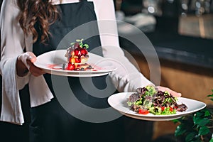 Waiter serving in motion on duty in restaurant. The waiter carries dishes.