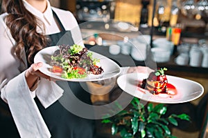 Waiter serving in motion on duty in restaurant. The waiter carries dishes.