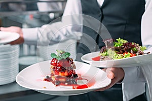 Waiter serving in motion on duty in restaurant. The waiter carries dishes.