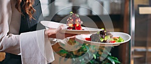 Waiter serving in motion on duty in restaurant. The waiter carries dishes