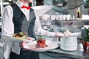 Waiter serving in motion on duty in restaurant. The waiter carries dishes