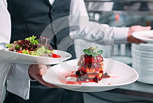 Waiter serving in motion on duty in restaurant. The waiter carries dishes