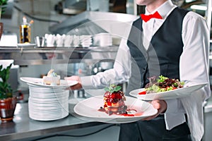 Waiter serving in motion on duty in restaurant. The waiter carries dishes.