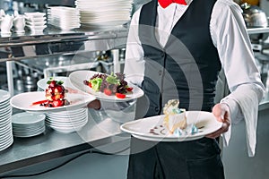 Waiter serving in motion on duty in restaurant. The waiter carries dishes