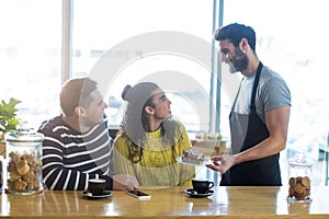 Waiter serving a plate of sandwich to customer