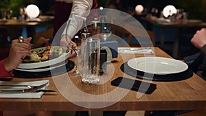 Waiter serving restaurant food to multiethnic couple at romantic dinner date.