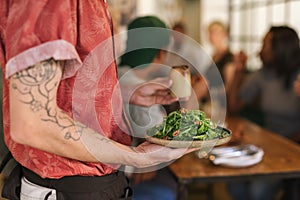 Waiter serving salad to customers sitting at a restaurant table