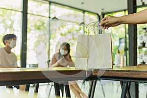 Waiter serving takeaway food to customer in small business social distance conceptual.