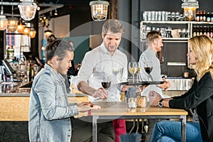 Waiter Serving Wine To Customers In Bar