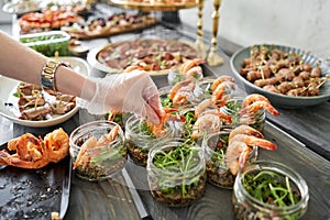 The waiter sets the table. Delicious fresh seafood, shrimp with fresh vegetables. buffet table with lots of delicious