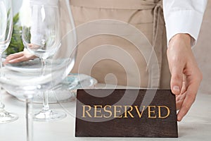 Waiter setting RESERVED sign on restaurant table