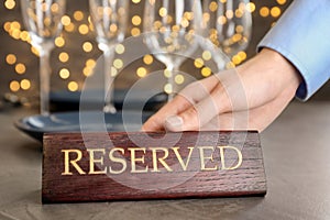 Waiter setting RESERVED sign on restaurant table