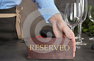 Waiter setting RESERVED sign on restaurant table