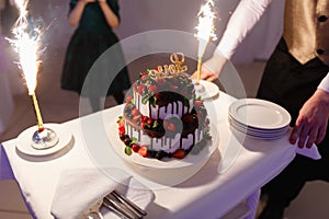 Waiter in the shape of the restaurant pulls out a beautiful wedding yogurt cake with the inscription love and burning fires with s