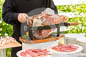 Waiter slicing italian ham, prosciutto