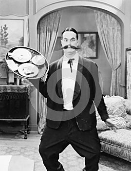 Waiter standing in a hotel room and trying to balance a serving tray