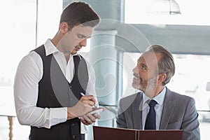 Waiter taking the order from a businessman