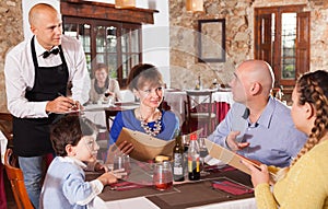 Waiter taking order of family at restaurant