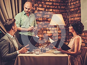 Waiter taking order from stylish wealthy couple