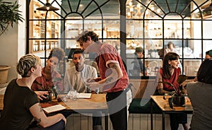 Waiter taking orders from customers sitting in a bistro