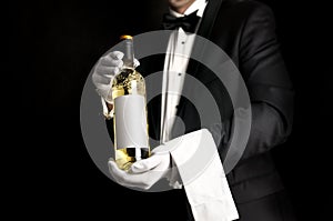 Waiter in tuxedo holding a bottel of white wine