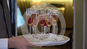 Waiter or waitress walks with tray and wine glasses alcoholic beverage champagne