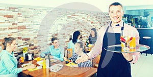 Waiter warmly welcoming guests to cozy family cafe