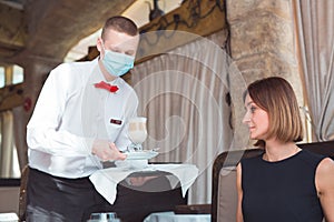 The waiter works in a restaurant in a medical mask
