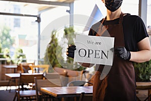 The waiter works in a restaurant in a medical mask, gloves during coronavirus pandemic