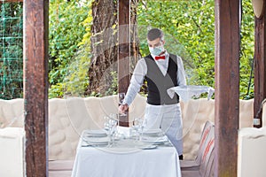 The waiter works in a restaurant on the summer terrace