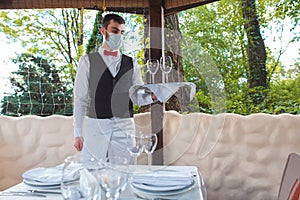 The waiter works in a restaurant on the summer terrace