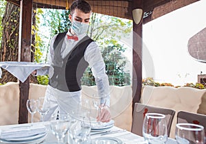 The waiter works in a restaurant on the summer terrace