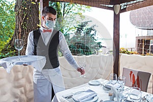 The waiter works in a restaurant on the summer terrace