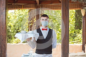 The waiter works in a restaurant on the summer terrace