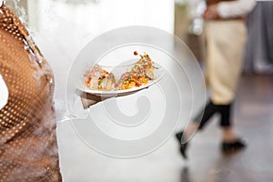 Waiters carrying plates with meat dish at a wedding