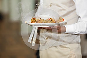 Waiters carrying plates with meat dish at a wedding