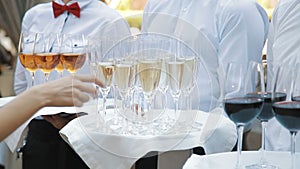 Waiters greet guests with alcoholic drinks. Champagne, red, white wine on trays