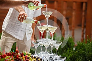 Waiters pour champagne on a pyramid of wineglasses