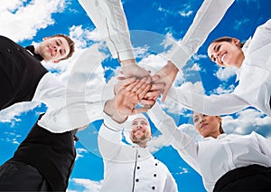 Waiters And Waitresses Stacking Hands Against Sky