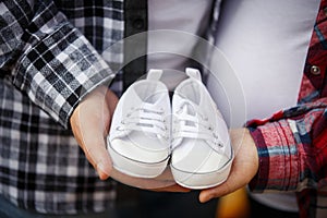 Waiting of baby-boy. Little white baby`s bootees in mom`s and da`s hands.