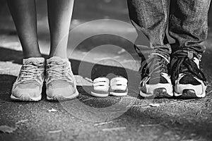 Waiting of baby. Little booties, sneakers near the feet of my father and mother. Pregnant woman, pregnancy, motherhood