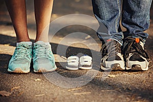 Waiting of baby. Little booties, sneakers near the feet of my father and mother. Pregnant woman, pregnancy, motherhood