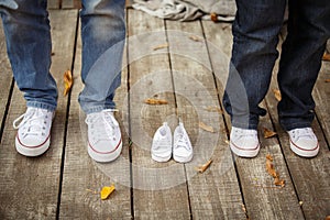 Waiting of baby. Little white baby`s bootees near mom`s and dad`s