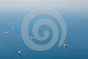 Waiting cargo ships in front of wind farm at the North Sea